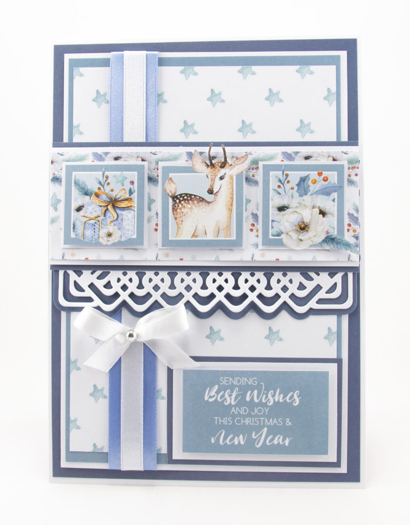 A Christmas card with a star backing paper, a deer image, presents and Christmas Roses.